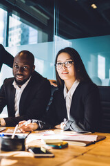Portrait of diverse male and female colleagues sitting at office desk and looking at camera during corporate meeting for together cooperate, experienced executive managers posing during conference