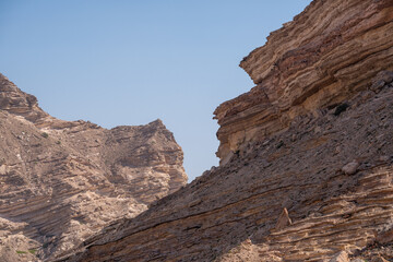 Geschichtete Felsformationen in der Wüste des Oman unter blauem Himmel