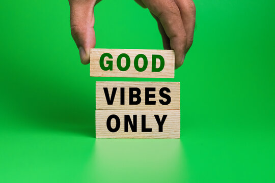 male hand put wooden blocks with good vibes only words isolated on green background