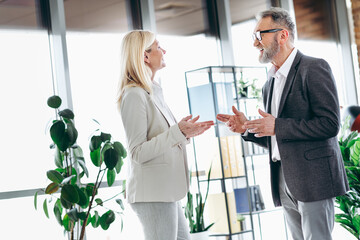 Obraz premium Senior businessman and businesswoman collaborating in modern office, discussing work strategies, building professional relationships