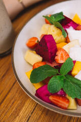 Cropped image of baked sweet granola in white plate with chopped fresh fruits for morning breakfast meal, top view of tasty sweet brunch food with homemade for healthy nutrition