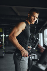 Vertical photo of handsome bodybuilder prepares himself mentally and physically for an intense and demanding workout on the parallel bars, aiming for maximum results