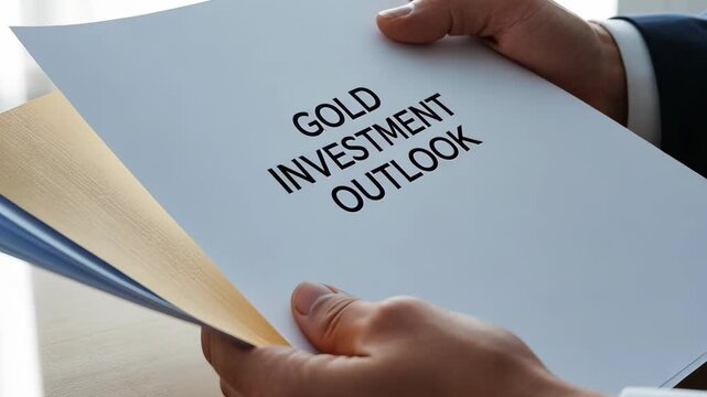 person holds document titled Gold Investment Outlook showcasing financial concept related to gold as valuable investment