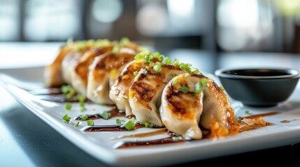 Deliciously browned, pan-fried dumplings, topped with green onions, served on a white plate with a side of dark soy sauce.