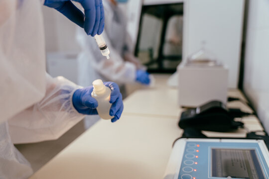 Close up of gloved hands filling syringe with breast milk for laboratory testing