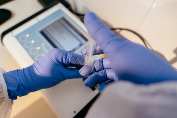 Close up of hands holding labeled breast milk jar in front of filled storage racks