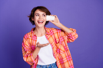 Portrait of nice young lady paper cup eavesdrop empty space wear shirt isolated on purple color...