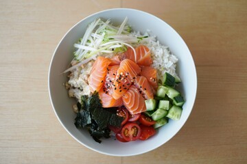 Hawaiian salmon fish poke bowl with rice, radish,cucumber, tomato, sesame seeds and seaweeds. Buddha bowl. Diet food