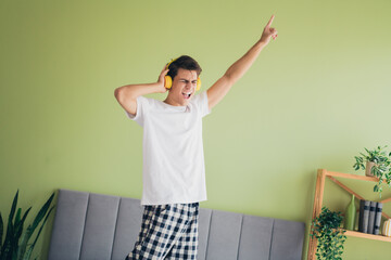 Young man enjoying leisure time wearing headphones, listening to music in a comfortable home...