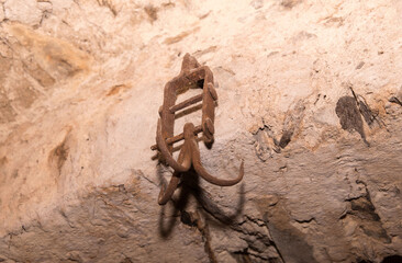 Ancient rusty metal hanger on stone wall in historic cave setting