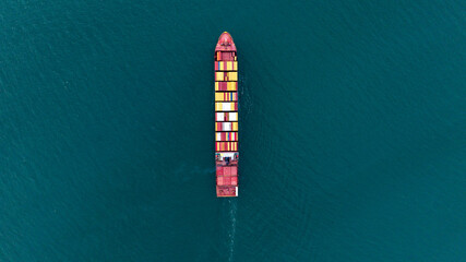 Top view Cargo Container ship with contrail in the ocean ship carrying container and running for import export concept technology freight shipping by ship.