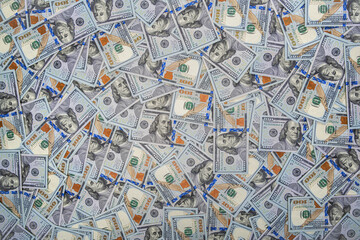 A chaotic spread of U.S. hundred-dollar bills fills the frame, creating a textured background symbolizing financial abundance, currency flow, and economic power.
