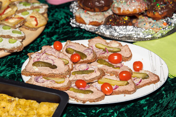 Assorted open-faced sandwiches with pickles, onions, and cherry tomatoes on dark bread