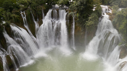 Multiple Waterfalls Cascading into a Pool Surrounded by Lush Greenery