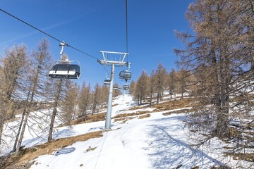 Obraz premium Ski lift on snowy mountain with blue sky and pine trees in winter landscape
