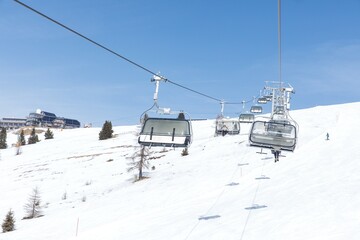Ski resort in winter with chairlifts on snowy mountain slope under blue sky