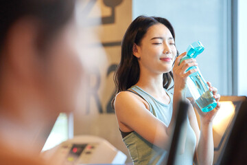 Young Asian Woman Hydrating at Gym