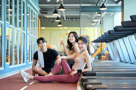 Two Asian Women and One Asian Man Relaxing at Gym