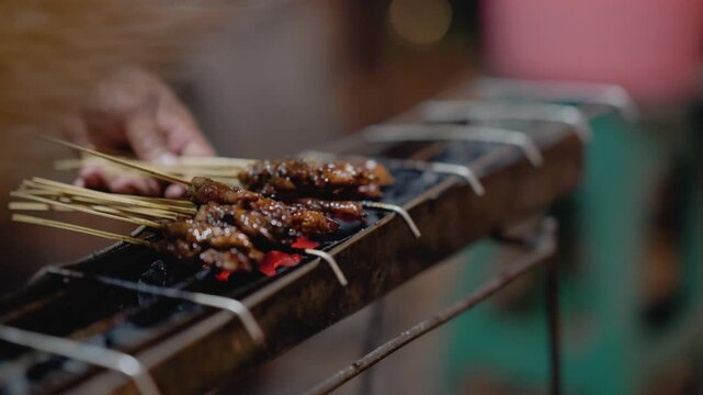 Street food vendor grilling satay, Grilled meat on skewer. Meat on the grill over coals of satay made from Indonesia.