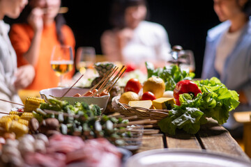 A group of people are gathered around a table with a variety of food