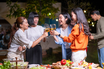 A group of women are gathered around a table, toasting with wine glasses