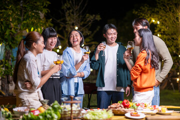 A group of people are gathered around a table with food and drinks