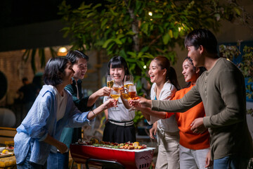 A group of people are gathered around a grill, drinking beer and celebrating