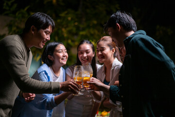 A group of people are gathered together, holding glasses of beer and smiling