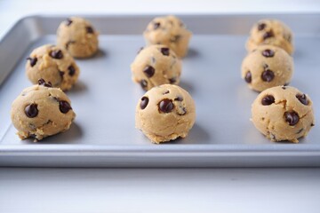 Chocolate chip cookie dough scoopes on a cookie sheet ready to be baked