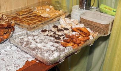 Assorted homemade pastries on tray with powdered sugar and lace tablecloth