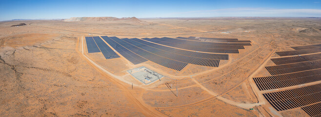 Expansive solar energy farm, grid of photovoltaic panels in vast arid landscape © South Africa Stock