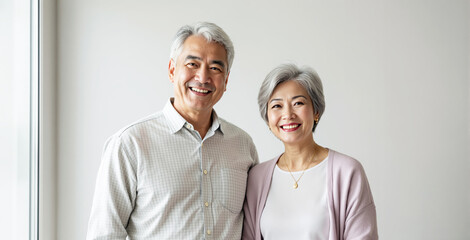 Happy senior couple smiling warmly at camera, natural photography style, plain indoor background, concept of aging gracefully and companionship. Ai generative