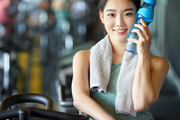 Young Asian Woman at Gym with Water Bottle and Towel