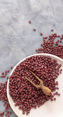Plate full of dried red azuki beans with a wooden scoop top view. East Asian legumes, vegetarian food