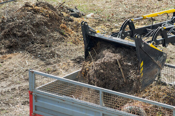 The loader's bucket is pouring waste into the van in the rays of the morning sun, close-up....