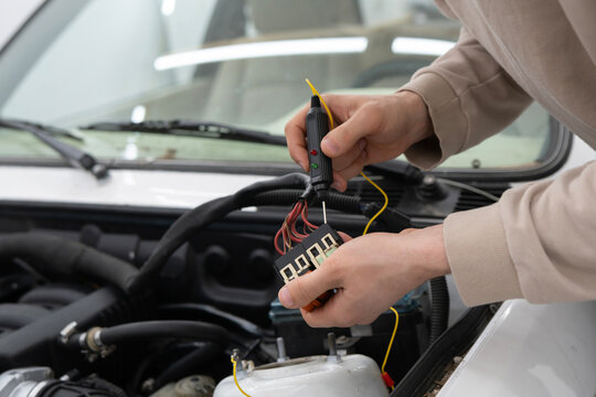 Car Mechanic Uses Auto Diagnostic Tester on Vehicle Engine to Identify Issues During Repair Process