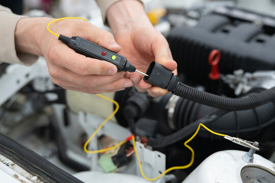 Car Mechanic Uses Auto Diagnostic Tester on Vehicle Engine to Identify Issues During Repair Process