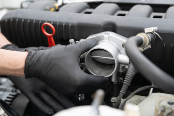 Car Mechanic Repairs Throttle Valve in an Automotive Workshop During a Busy Morning Session