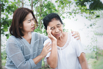 elderly asian woman feel dizzy and almost faints while walking outside caused by weakness or hot weather , her daughter quickly holds and hugs to help her safe, showing care and support
