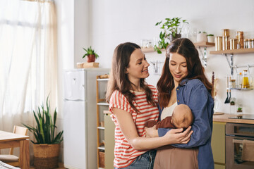 Two loving mothers celebrate Mothers Day in a cozy home with their child surrounded by warmth
