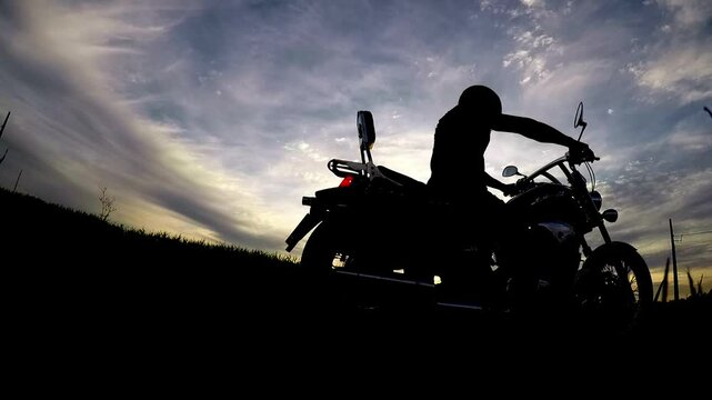 silhueta de motoqueiro na estrada 