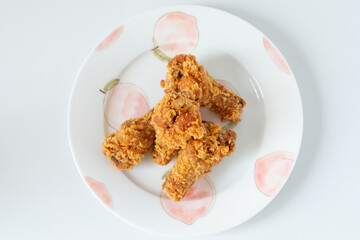 Asian Chinese food style 4 deep fried spicy chicken wings gourmet snacks on a ceramic plate, close up on white background