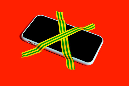Colorful still life of a banned smartphone with cross-hatched adhesive tape symbolizing digital detox and mindfulness