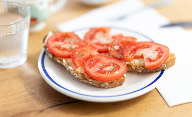 Two bruschettas with tomato slices on a plate