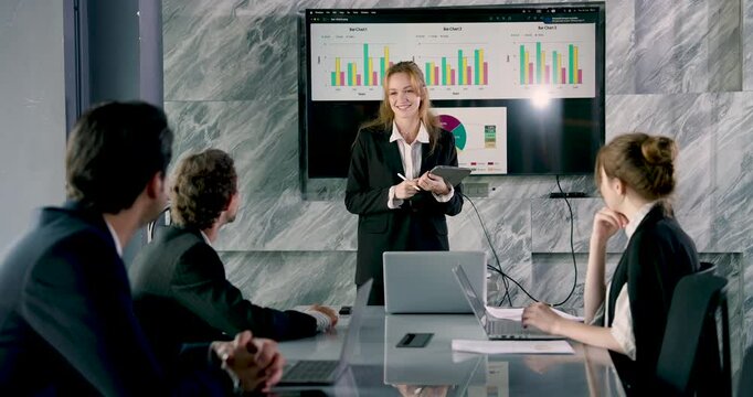 Young female executive delivering presentation using digital tablet in front of business team during meeting demonstrating leadership, digital fluency and active engagement in corporate workspace