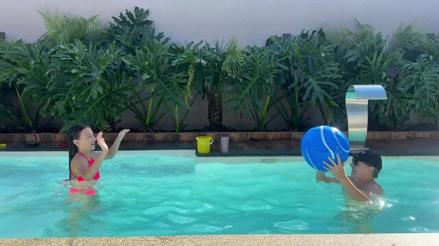 av&oacute; e neta brincam com bola em piscina nas f&eacute;rias de ver&atilde;o 