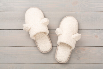 Soft teddy slippers on wooden background, top view