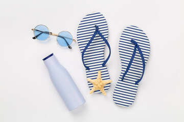 Striped blue flip flops with accessories on color background, top view