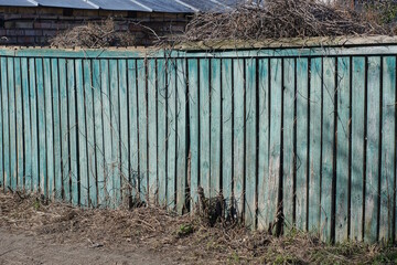 old long green gray wooden wall fence from boards on the rural street
