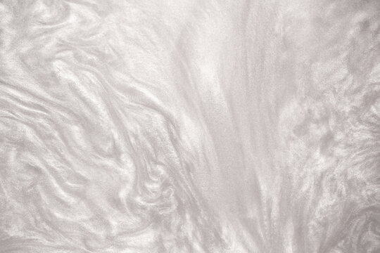 Fototapeta Shimmering silver abstract background. Liquid glitter paint texture waves and swirls. Beautiful shiny white glitter texture. Metallic silver paint close-up as a holiday background.